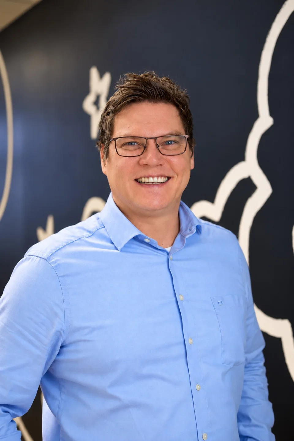 Florian Kümper lächelt im hellblauen Hemd.
